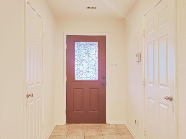 doorway featuring baseboards, visible vents, and light tile patterned flooring