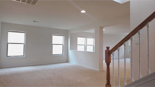 empty room with carpet flooring, visible vents, baseboards, and stairs