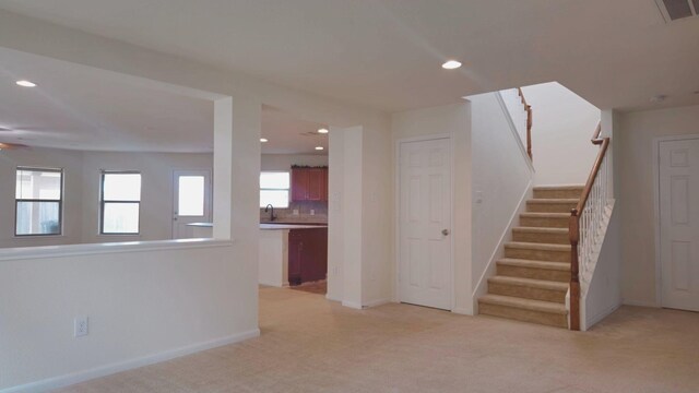 spare room with baseboards, visible vents, light colored carpet, stairs, and a sink