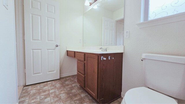 bathroom with vanity, toilet, and baseboards