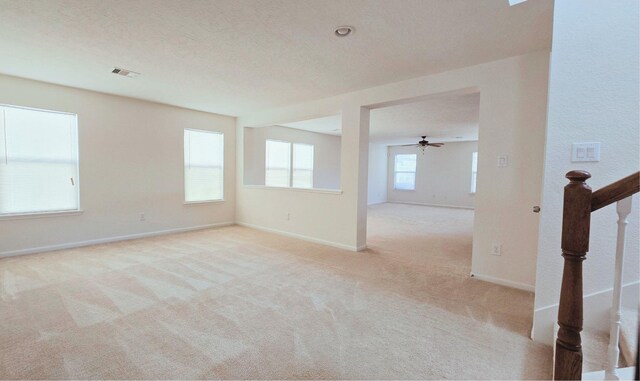 empty room with carpet floors, visible vents, a textured ceiling, baseboards, and stairs