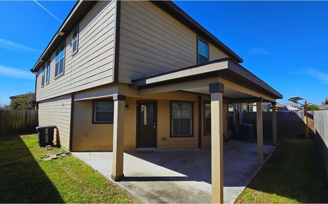 rear view of property with a patio area, a fenced backyard, central AC unit, and a lawn