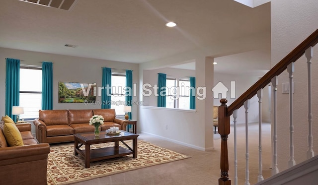 carpeted living room with stairs, visible vents, and a healthy amount of sunlight