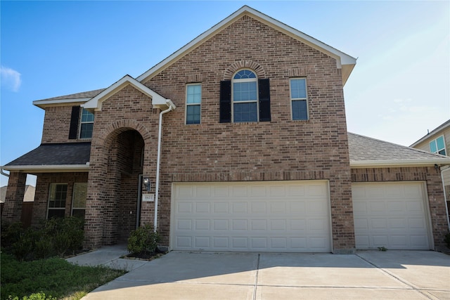 traditional home with concrete driveway, brick siding, and a shingled roof