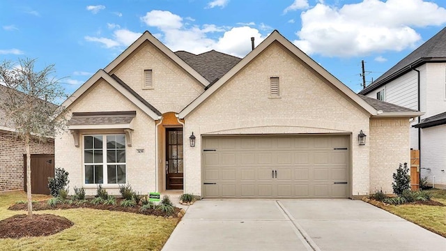 7439 Denali Dr, Katy, TX 77493 - french country style house featuring concrete driveway, a shingled roof, an attached garage, and brick siding