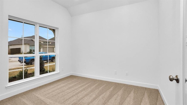 carpeted spare room featuring vaulted ceiling and baseboards