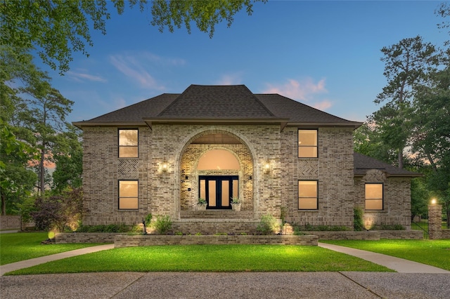 french country home featuring a yard and brick siding