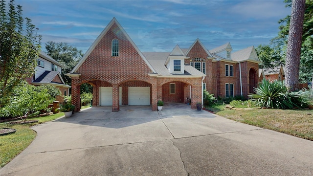 tudor home featuring concrete driveway and brick siding