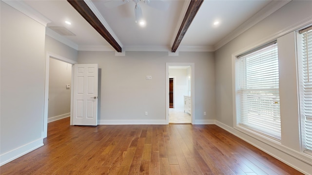 spare room featuring ceiling fan, hardwood / wood-style flooring, visible vents, baseboards, and beamed ceiling