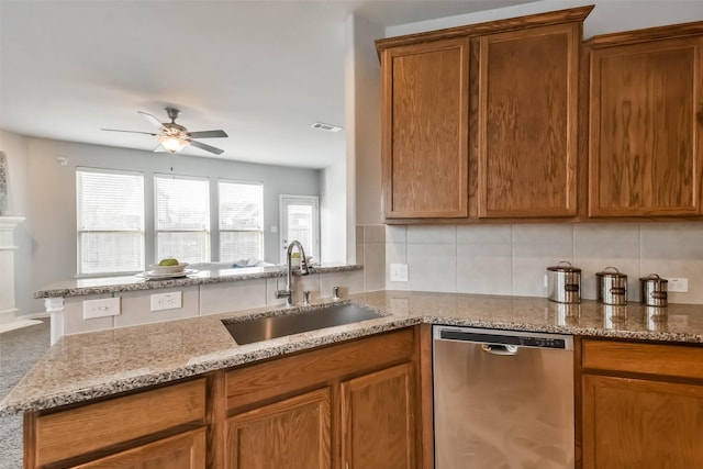 kitchen with visible vents, dishwasher, light stone counters, backsplash, and a sink