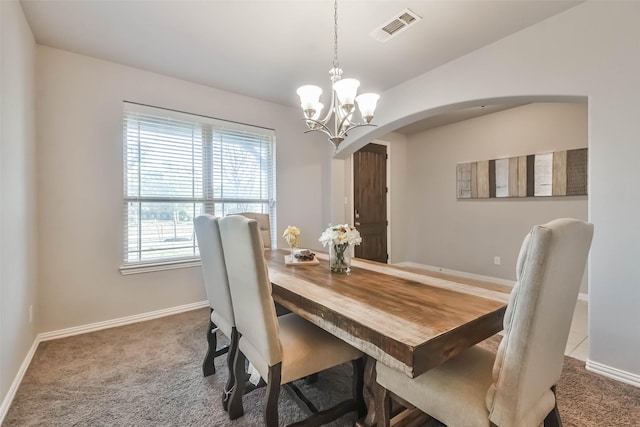 carpeted dining space with arched walkways, lofted ceiling, visible vents, baseboards, and an inviting chandelier