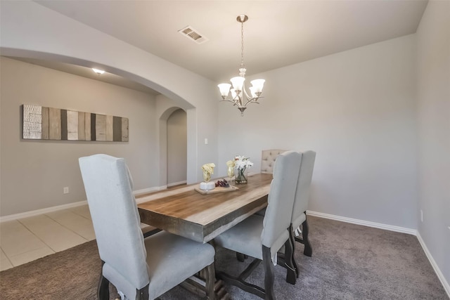 dining space with baseboards, visible vents, arched walkways, an inviting chandelier, and carpet flooring