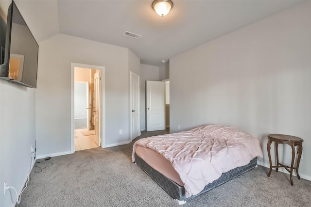 bedroom featuring carpet, lofted ceiling, visible vents, ensuite bath, and baseboards