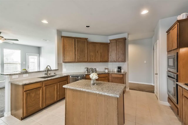 kitchen with appliances with stainless steel finishes, backsplash, a sink, and light stone counters