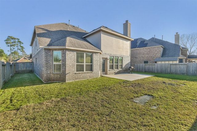 back of house featuring a fenced backyard, brick siding, a shingled roof, a yard, and a patio area