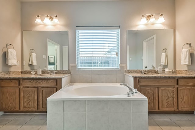 full bathroom featuring a garden tub, tile patterned flooring, two vanities, and a sink