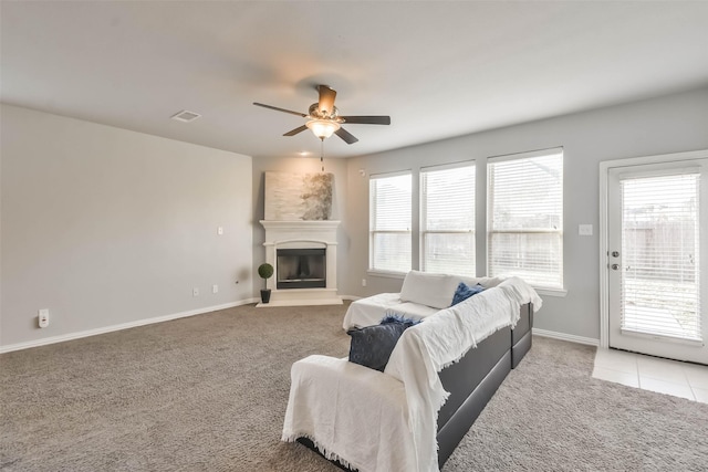 carpeted living area featuring visible vents, baseboards, a ceiling fan, and a glass covered fireplace