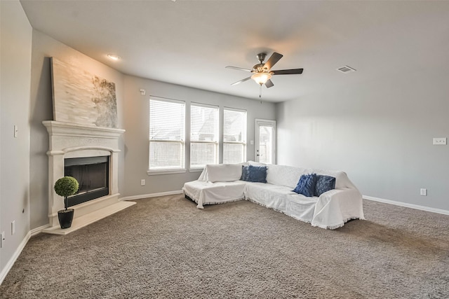 living room with carpet floors, baseboards, visible vents, and a fireplace with raised hearth