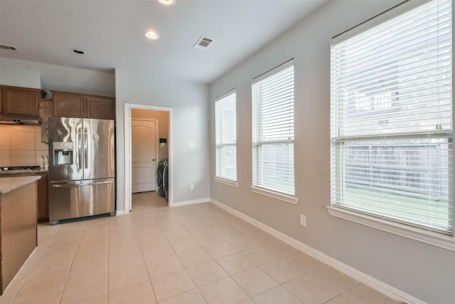 kitchen featuring tasteful backsplash, visible vents, light tile patterned flooring, washer / dryer, and stainless steel fridge with ice dispenser