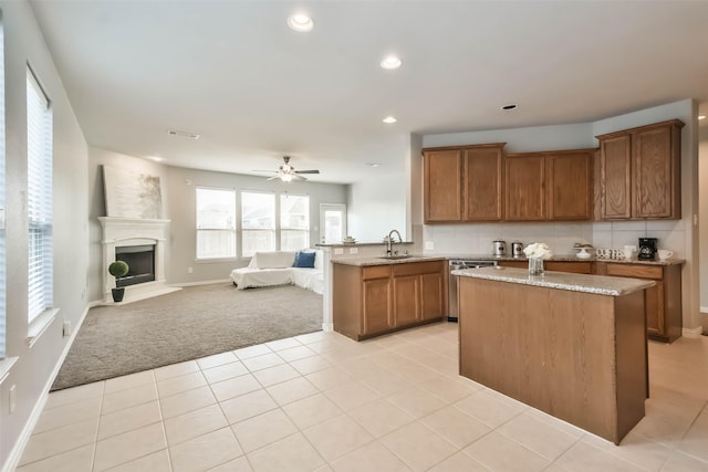 kitchen with open floor plan, brown cabinetry, a sink, and light colored carpet