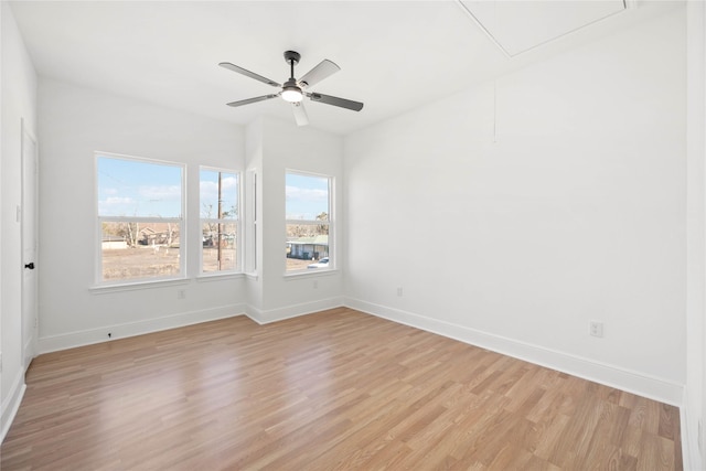 spare room with light wood-style floors, attic access, and baseboards