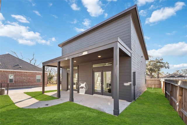 back of property with a fenced backyard, a lawn, french doors, and a patio