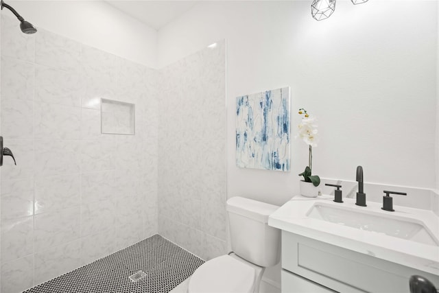 bathroom featuring tiled shower, vanity, and toilet