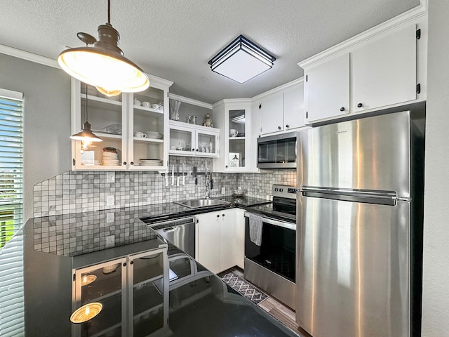 kitchen with stainless steel appliances, dark countertops, a sink, and white cabinets