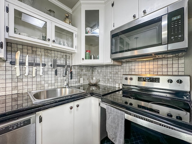 kitchen with stainless steel appliances, dark countertops, tasteful backsplash, white cabinetry, and a sink