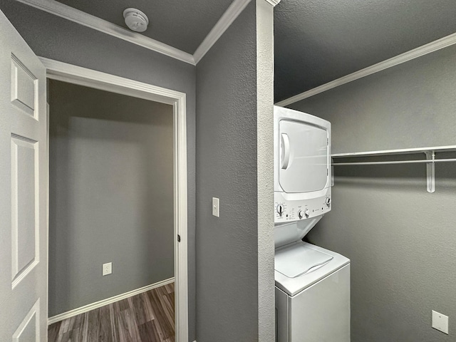 washroom featuring stacked washer and dryer, laundry area, a textured wall, wood finished floors, and crown molding