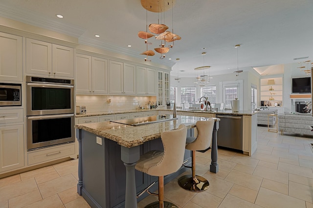 kitchen featuring stainless steel appliances, decorative backsplash, open floor plan, a sink, and a peninsula