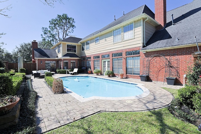 rear view of house with a patio area, a chimney, an outdoor living space, and brick siding