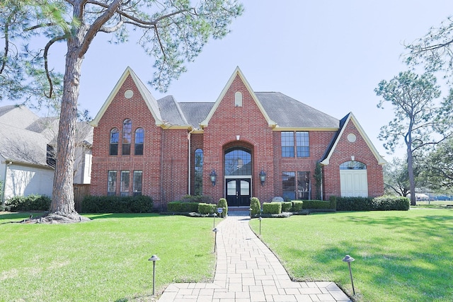 view of front of home with french doors, brick siding, and a front lawn