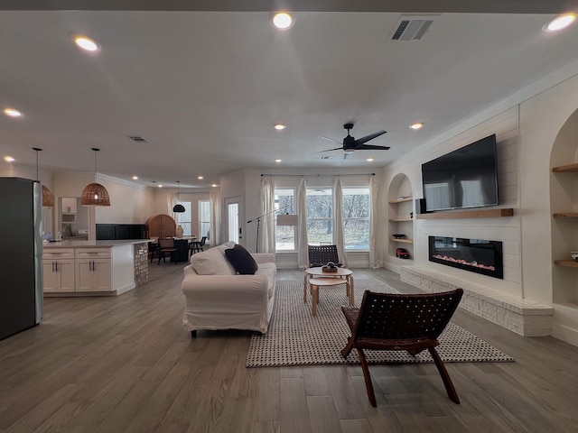 6804 Broadleaf Dr, Beaumont, TX 77708 - living area with built in features, recessed lighting, wood finished floors, a glass covered fireplace, and a ceiling fan