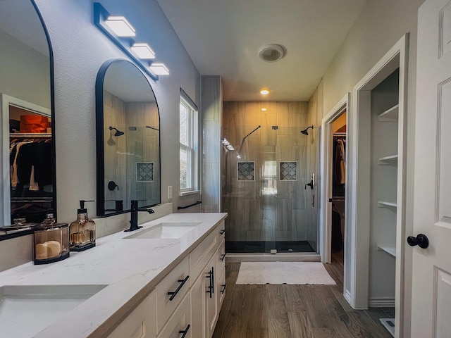 6804 Broadleaf Dr, Beaumont, TX 77708 - bathroom featuring a walk in closet, double vanity, a stall shower, and wood finished floors