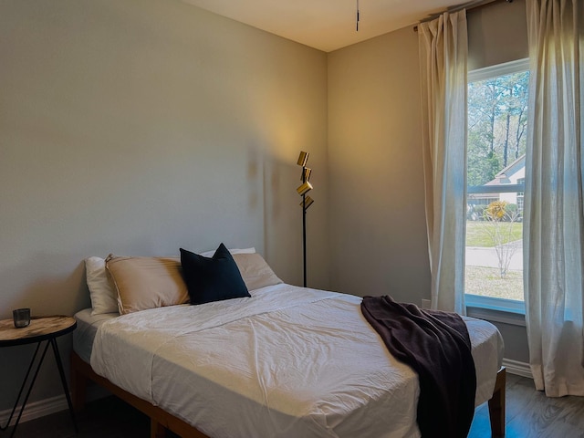 bedroom with multiple windows, baseboards, and wood finished floors