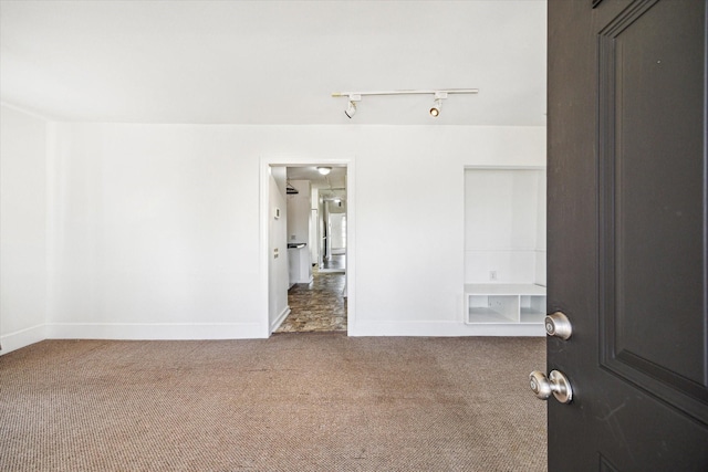 unfurnished room featuring rail lighting, baseboards, and carpet floors