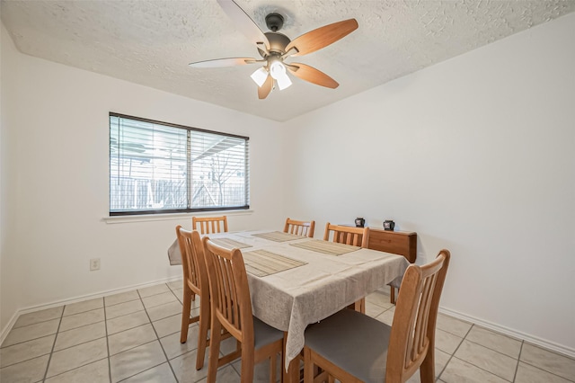 dining space with a ceiling fan, light tile patterned flooring, a textured ceiling, and baseboards