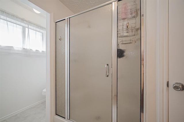 full bath featuring a stall shower, toilet, and baseboards