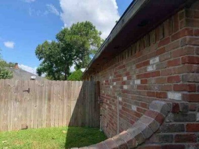 view of side of home with brick siding and fence