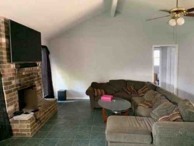 living area with vaulted ceiling with beams, dark tile patterned flooring, a fireplace, and a ceiling fan