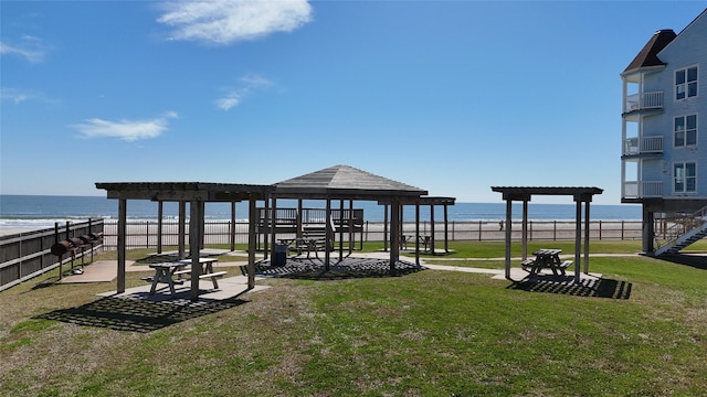 view of home's community with a yard, a water view, and fence