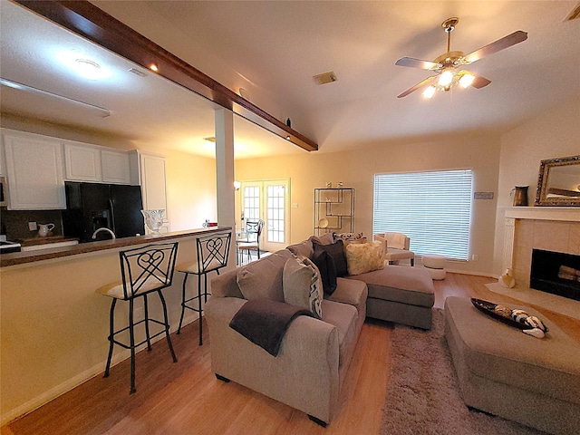 living room with ceiling fan, light wood-type flooring, a tile fireplace, and visible vents