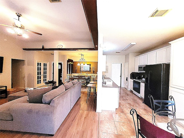 kitchen with visible vents, white cabinets, black fridge, stainless steel microwave, and gas stove