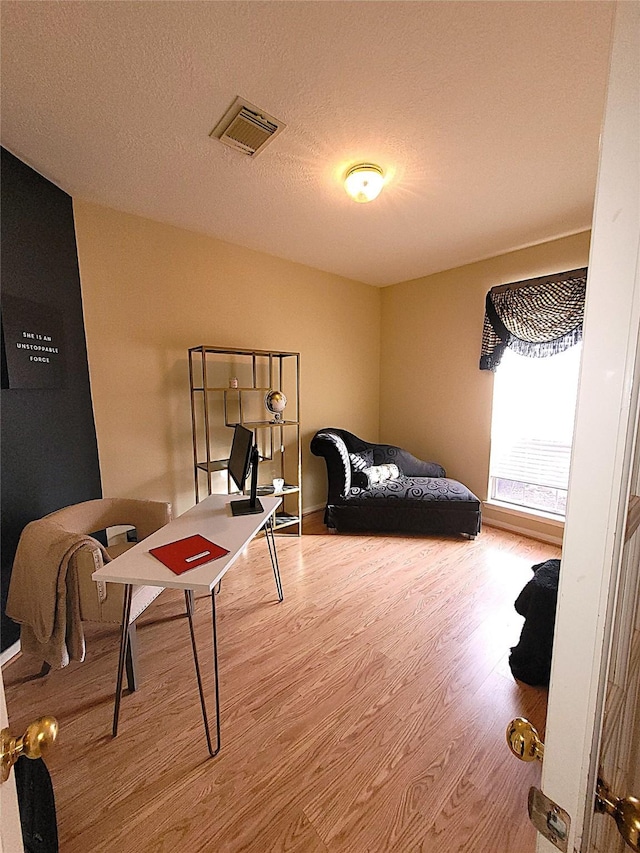 bedroom with visible vents, a textured ceiling, and wood finished floors