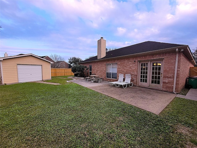 back of house with a lawn, a patio, a chimney, fence, and brick siding