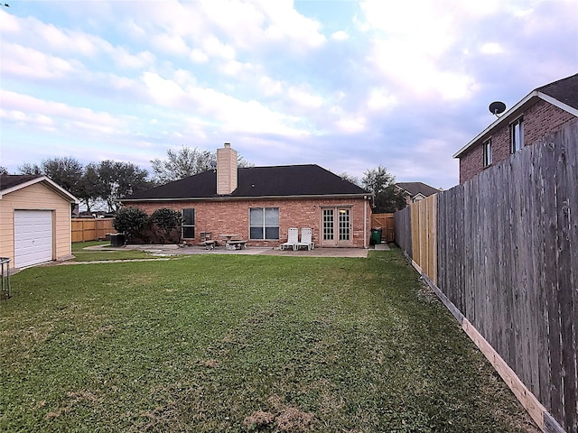 back of property featuring a fenced backyard, brick siding, a lawn, a chimney, and a patio area