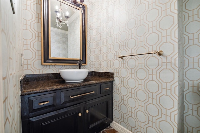 bathroom with vanity, baseboards, and wallpapered walls