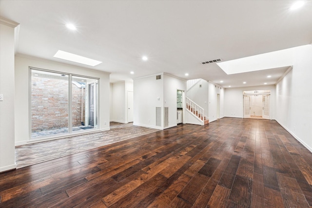 unfurnished living room featuring a skylight, visible vents, stairway, hardwood / wood-style floors, and crown molding