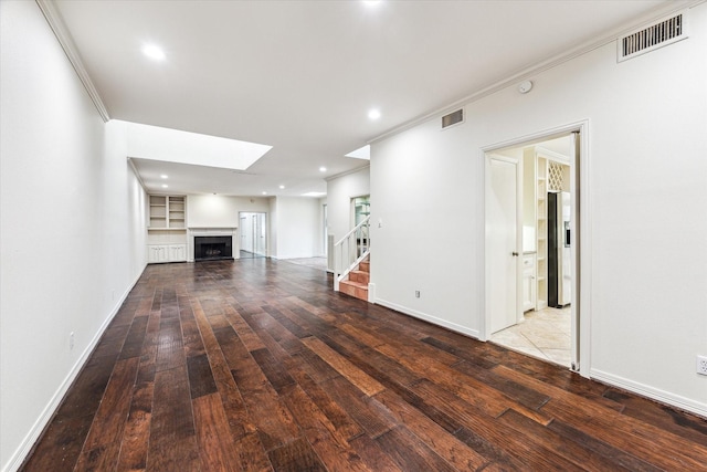 unfurnished living room with hardwood / wood-style floors, stairway, a fireplace, and visible vents